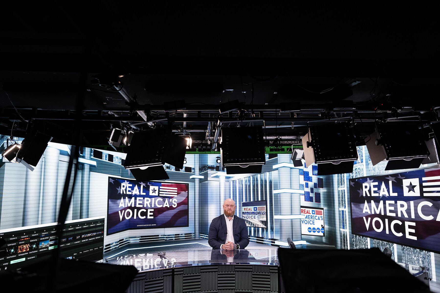 A guest seated at the anchor desk on the Real America's Voice news set