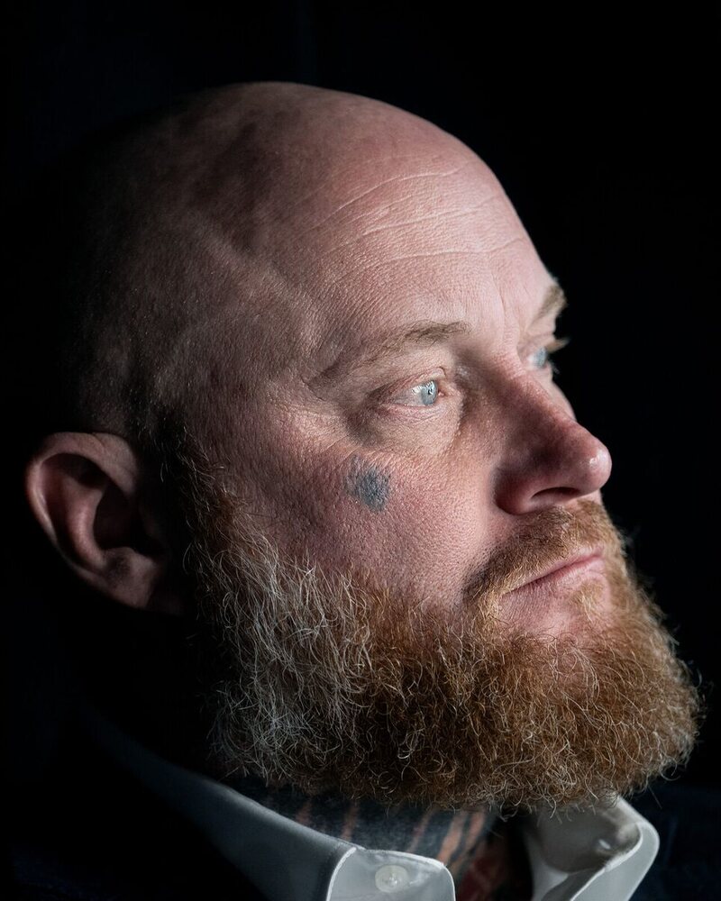 Portrait of Shane Jenkins, Stand in the Gap co-founder, looking off to the side against a dark background